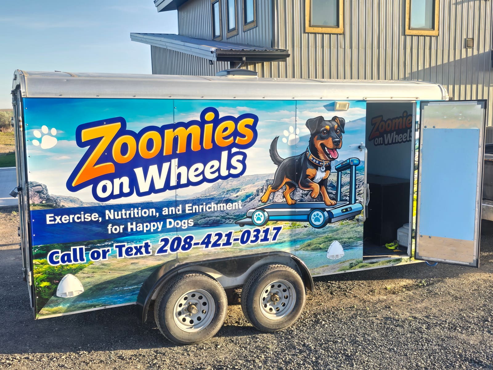 The Zoomies on Wheels trailer parked in a driveway at sunset, door open and ready